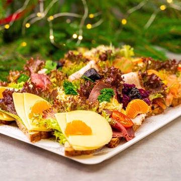 Bilde av et elegant fat med julesnitter, vakkert anrettet med sesongens smaker. Snittene inkluderer saftige reker med majones, mild edamerost med frukt, klassisk ribbe med rødkål og svisker, gravet laks med hjemmelaget sennepssaus, samt mørt roastbiff med grov remulade. Perfekt for julelunsj, julebord og høytidelige sammenkomster.