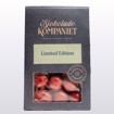 Glinsende drasjert lakriskaramell dekket i sjokolade med rødlig overflate, elegant presentert i pose – en fristende kombinasjon av lakris, sjokolade og et hint av jordbær.