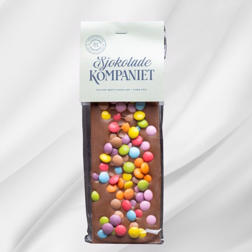 Bilde av Barnas Favoritt sjokoladeplate fra Sjokoladekompaniet, laget med en kombinasjon av myk melkesjokolade, søt karamellsjokolade og fargerike sjokoladelinser. En festlig og smakfull sjokoladeopplevelse som passer perfekt til bursdager og koselige stunder.