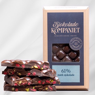 Bilde av mørk sjokoladeplate med bringebær og pistasjnøtter fra Sjokoladekompaniet. Laget med 61 % kakao for en fyldig og aromatisk smak, balansert med syrlige bringebær og delikate pistasjnøtter. En vegansk sjokoladeopplevelse som kombinerer fruktige og nøtteaktige toner i en elegant presentasjon.
