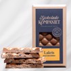 Bilde av sjokoladeplate med salt lakris fra Sjokoladekompaniet, laget med en harmonisk blanding av karamell- og melkesjokolade. Toppet med grovknuste biter av salt lakris-sukkertøy for en sprø og intens smaksopplevelse. En spennende kombinasjon av søtt, salt og knasende tekstur, perfekt for lakris- og sjokoladeelskere.