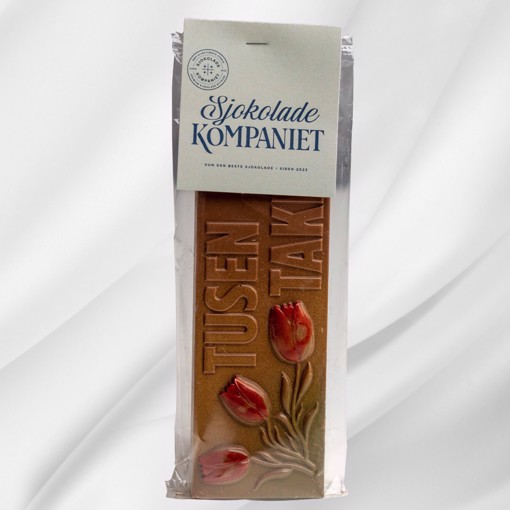 Bilde av en sjokoladeplate i melkesjokolade og karamellsjokolade med teksten Tusen takk! preget på toppen. Ligger på lys bakgrunn og formidler takknemlighet på en søt og oppriktig måte.