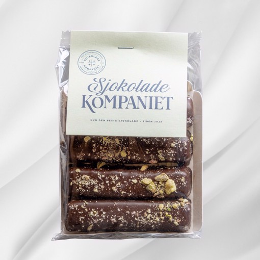 Bilde av et brett med fire veganske marsipanstenger laget av fin marsipan, trukket i 61 % mørk sjokolade og drysset med hakkede pistasjnøtter. Perfekt som en luksuriøs godbit til kaffe, påskeegg eller en smakfull pause.