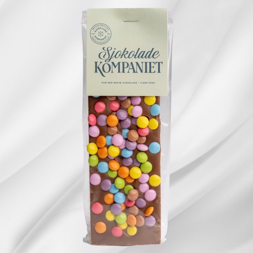 Bilde av Barnas Favoritt sjokoladeplate fra Sjokoladekompaniet, laget med en kombinasjon av myk melkesjokolade, søt karamellsjokolade og fargerike sjokoladelinser. En festlig og smakfull sjokoladeopplevelse som passer perfekt til bursdager og koselige stunder.